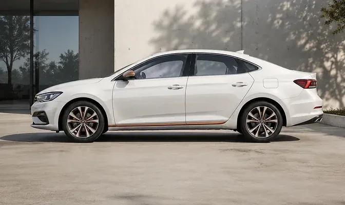 White sedan with a copper side line beside a modern concrete wall.
